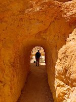 Long empty tunnel through golden rock with back of man at the far end