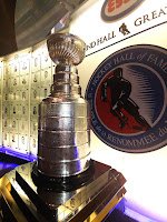 Hockey trophy crafted as Lord Stanley's cup. It is silver with bands wrapping a cylindrical base engraved with the names of every player from every National Hockey League championship team each year.